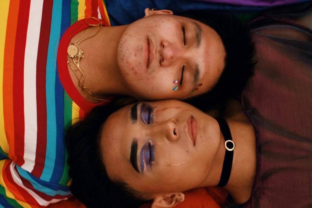 Close-up portrait of a couple embracing love and diversity with bold rainbow colors and expressive makeup.